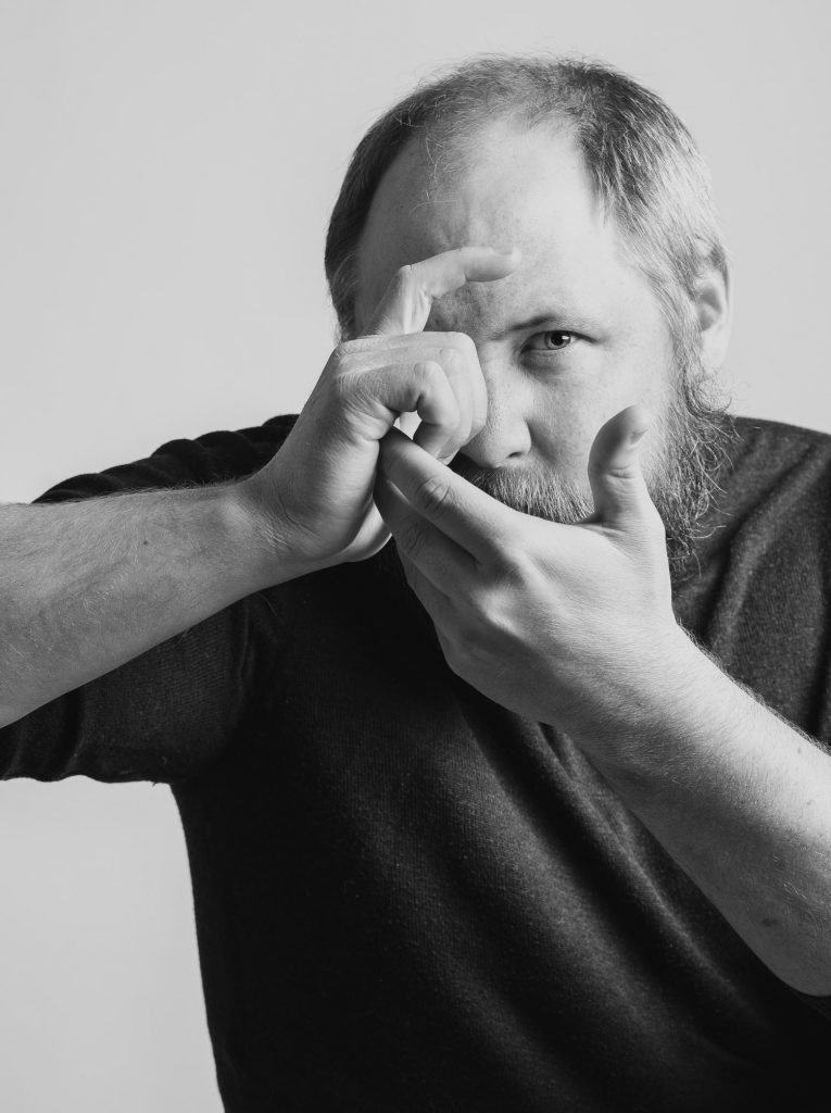 Bild på fotograf Björn Dahlfors. Han formar händerna som om han fotograferade.