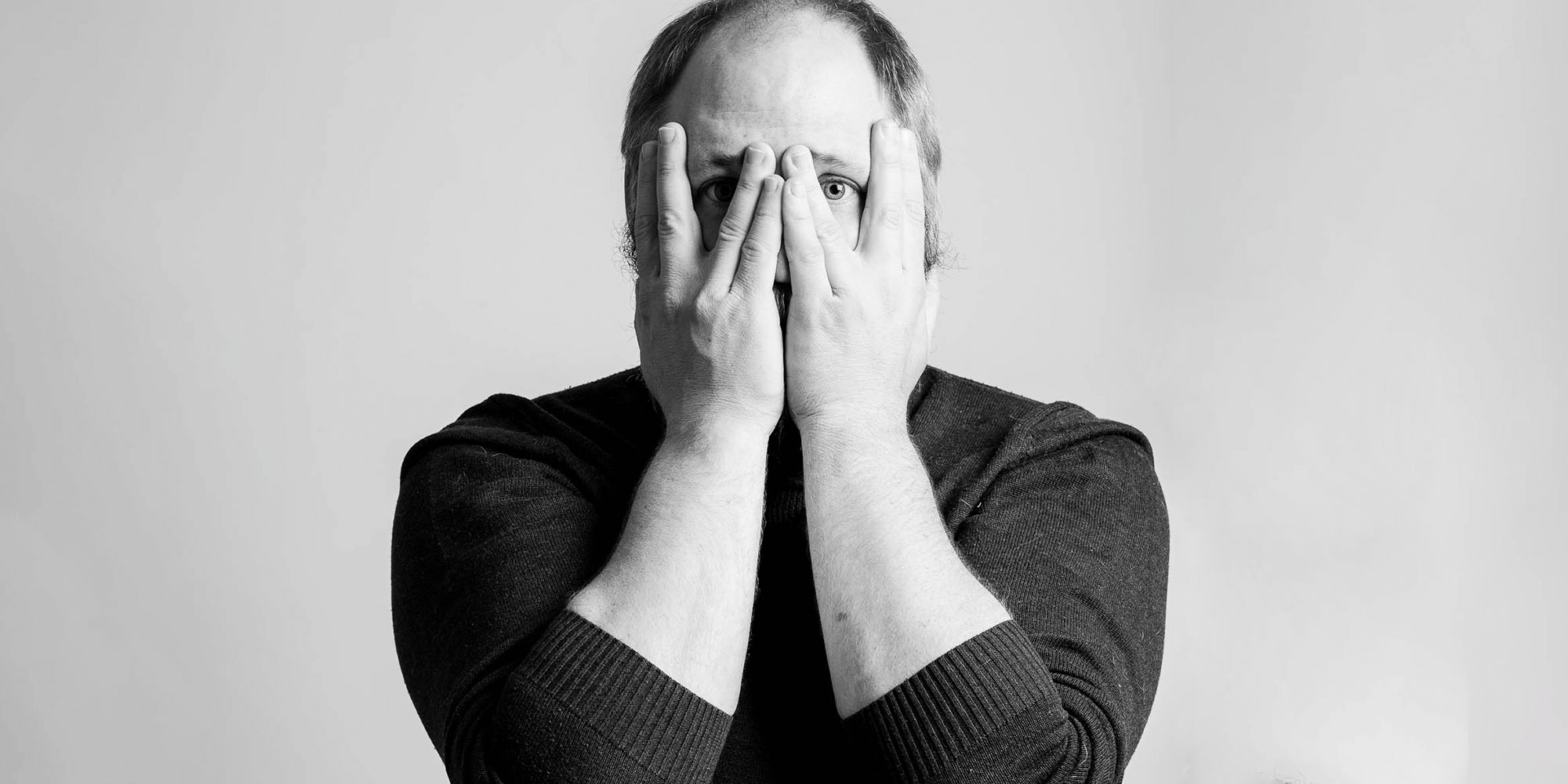 Fotograf Björn Dahlfors håller händerna framför ansiktet.